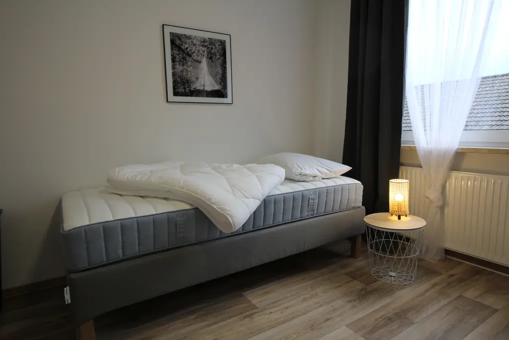 Einzelbett mit Lampe und Fenster