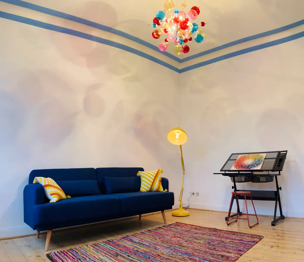ARTstudio 5.0: blaues Sofa, Zeichentisch und bunter Kronleuchter