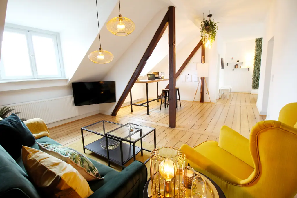 Dachgeschoss-Wohnzimmer mit gelbem Sessel, Sofa und Blick zum Essbereich