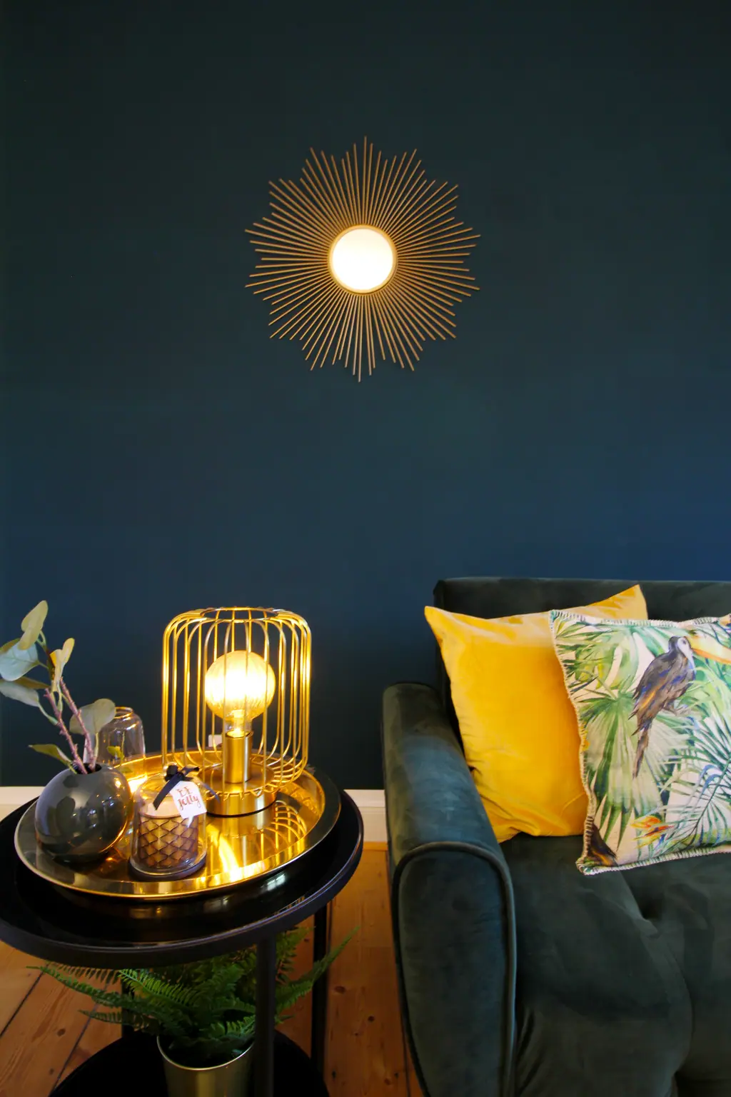 Goldene Käfiglampe und gelbe Kissen vor dunkelblauer Wand