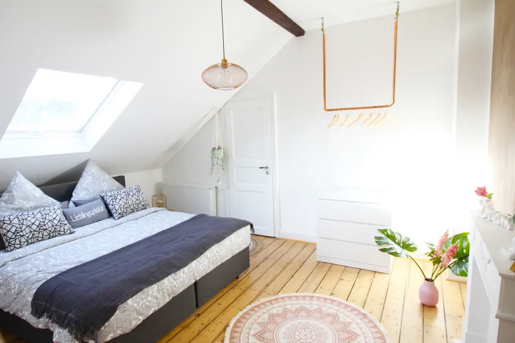 Schlafzimmer unter dem Dach mit Dachfenster und Kleiderstange