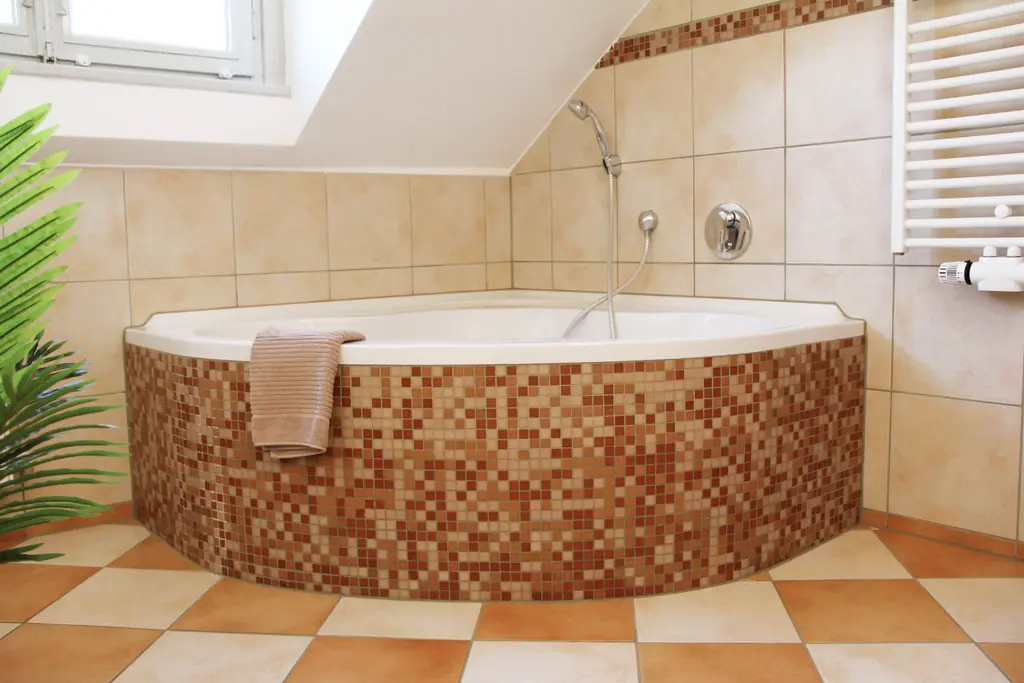 Eckbadewanne mit Mosaikfliesen unter der Dachschräge