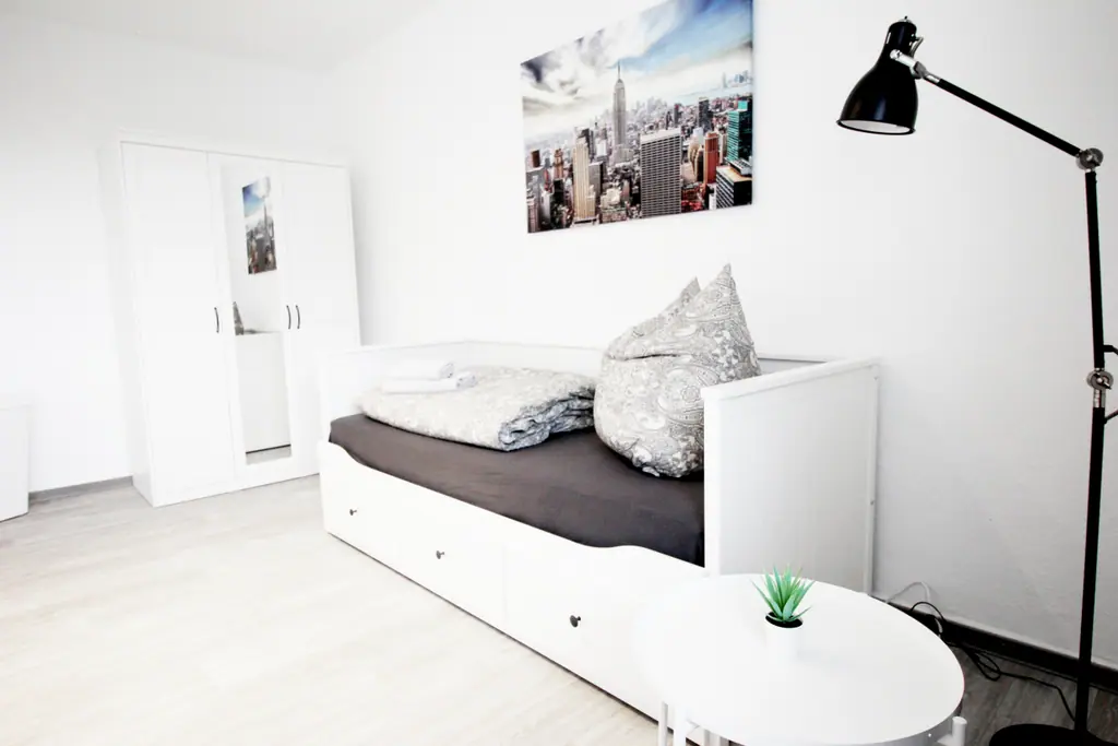 Schlafzimmer mit Einzelbett, grauer Bettwäsche und Skyline-Bild