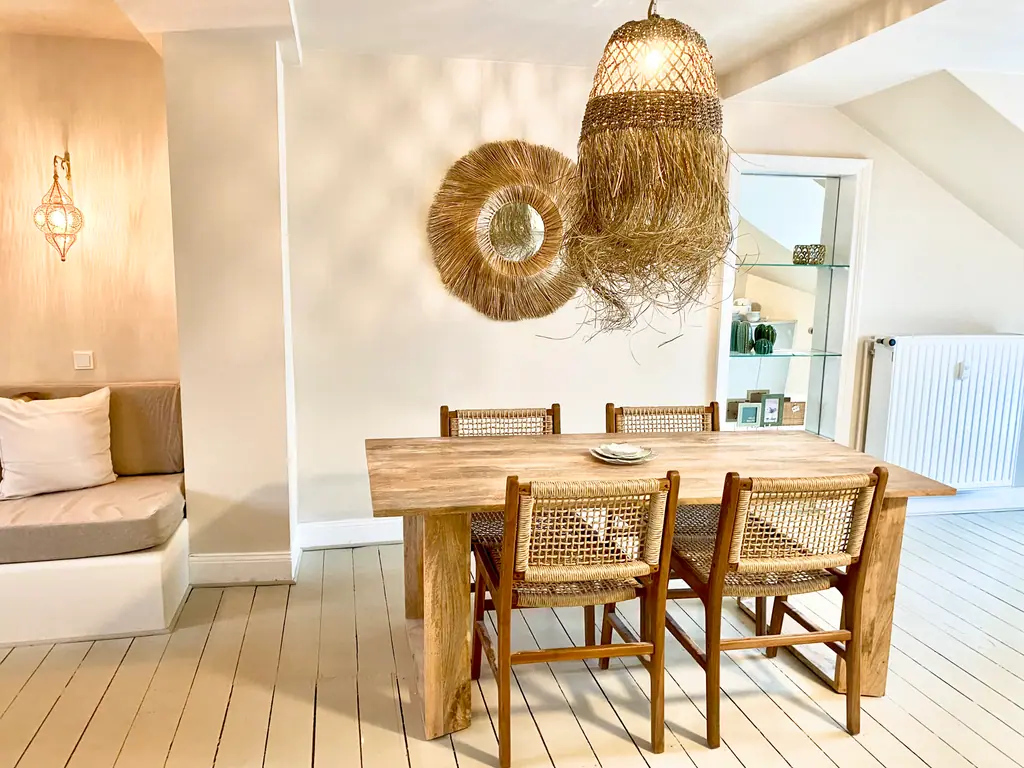 Esstisch aus Holz mit Rattanstühlen und Rattanlampe