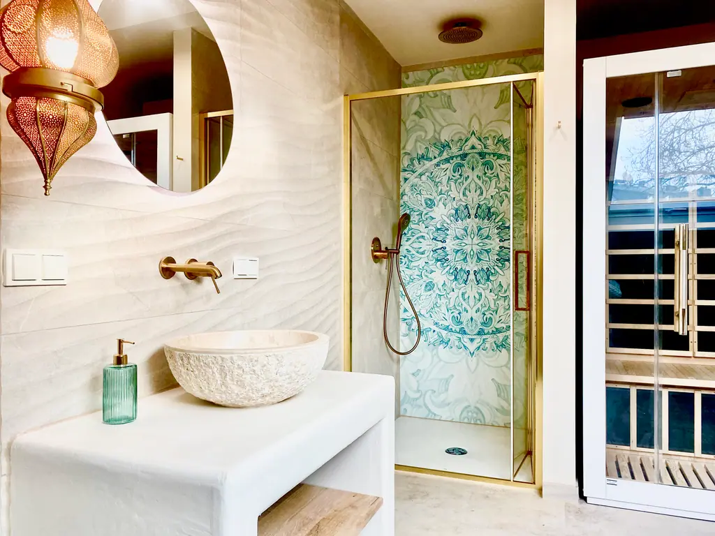 Dusche mit türkisfarbenem Mosaik, goldener Armatur und Steinwaschbecken