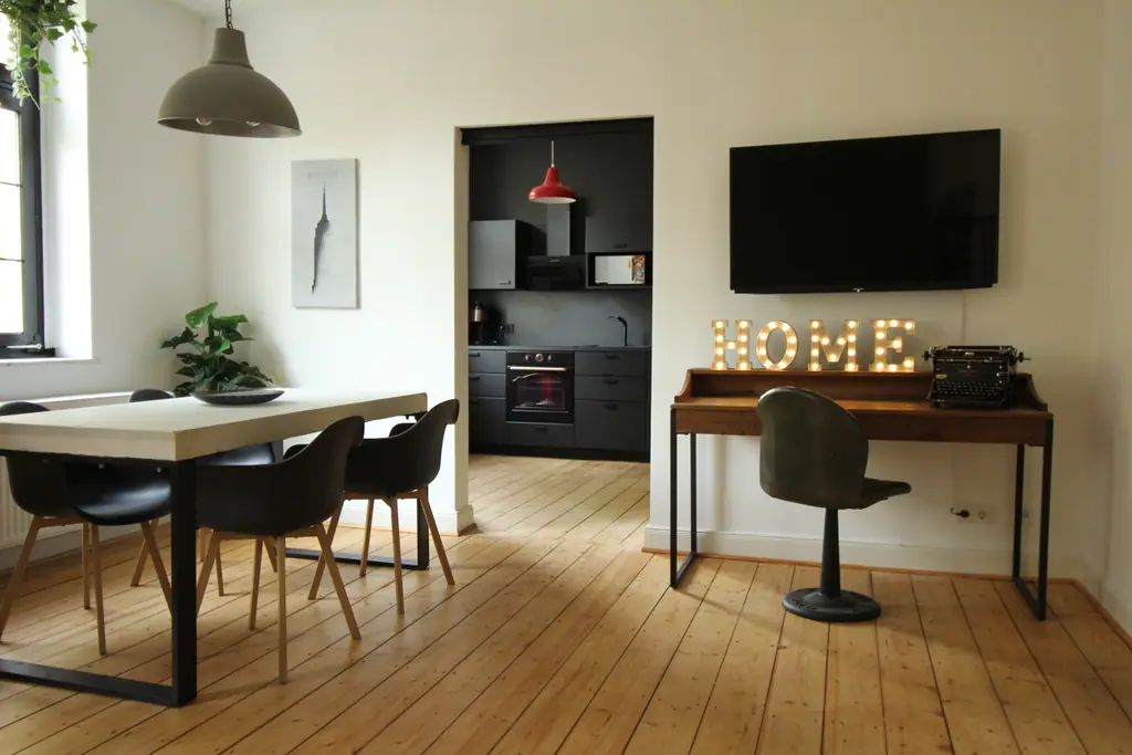 Schreibtisch mit leuchtenden HOME-Buchstaben und Fernseher