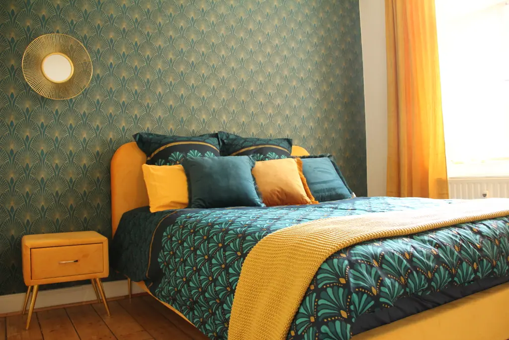 Schlafzimmer mit petrolfarbener Art-déco-Tapete und gelben Akzenten