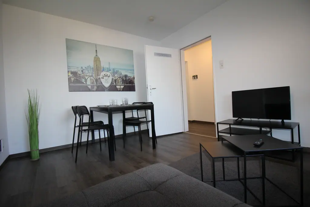 Rooftop Lodge: Wohnbereich mit Esstisch, Sofa und Fernseher unter dem Dach