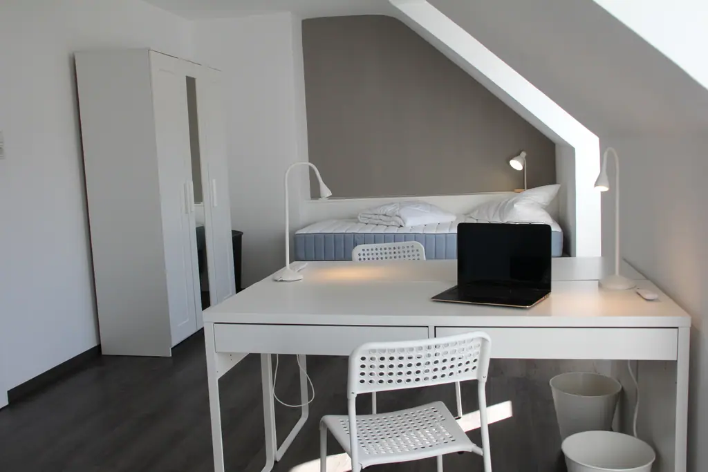 Schlafzimmer mit Einzelbett, Schreibtisch und Laptop