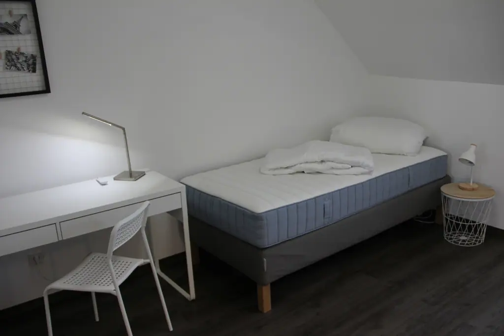 Einzelbett mit Schreibtisch und Lampe
