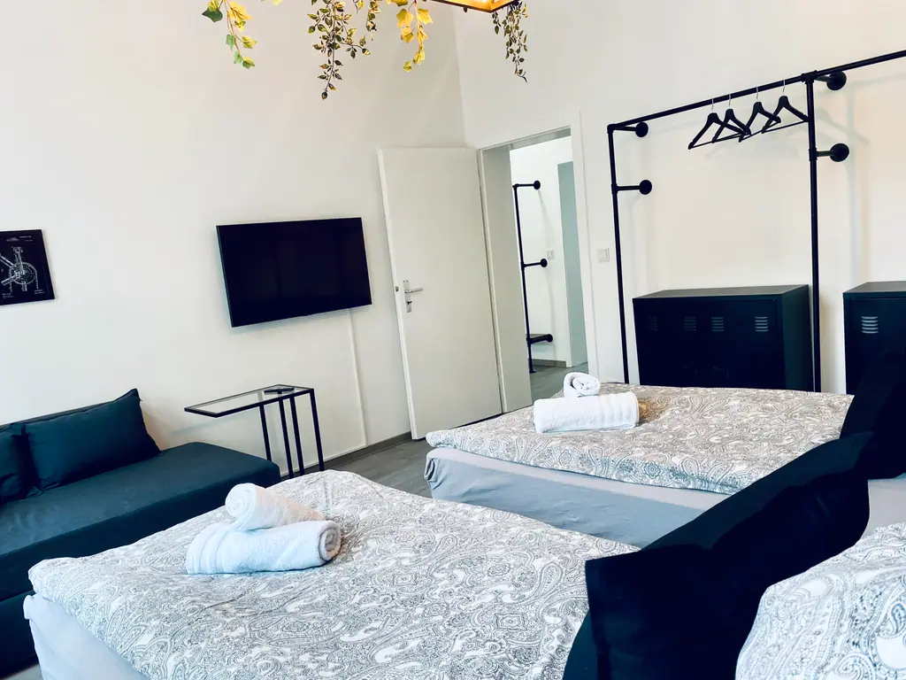 SH Team 1.0: Schlafzimmer mit zwei Einzelbetten, Sofa und Fernseher
