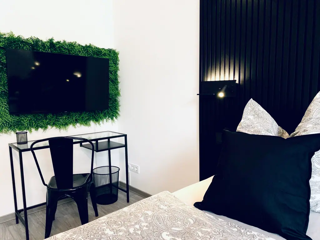 Zweites Schlafzimmer mit Bett, Schreibtisch und Mooswand