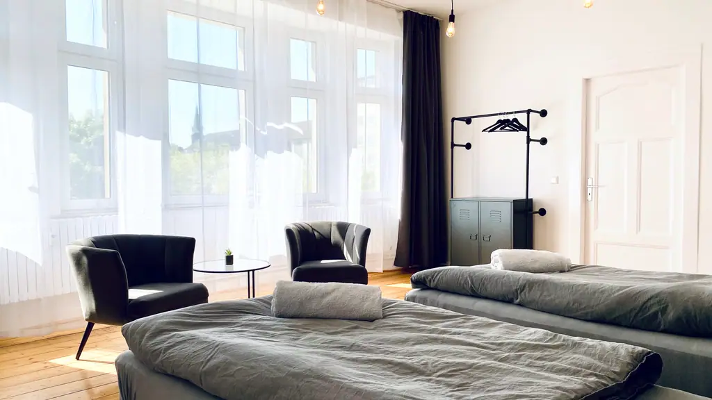 Schlafzimmer mit zwei Einzelbetten und Sesseln am Fenster