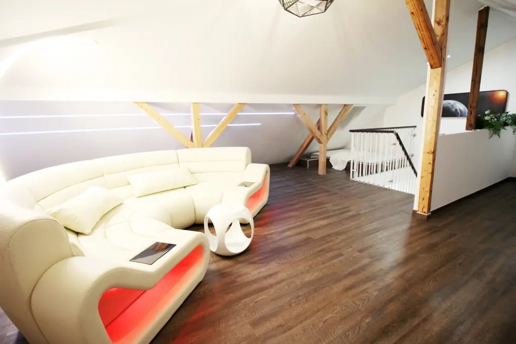Space Loft: weiße Lounge mit geschwungenem Sofa unter Dachbalken