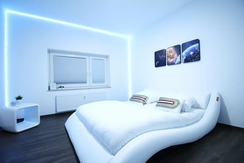 Schlafzimmer mit rundem weißem Bett und blauer LED-Beleuchtung