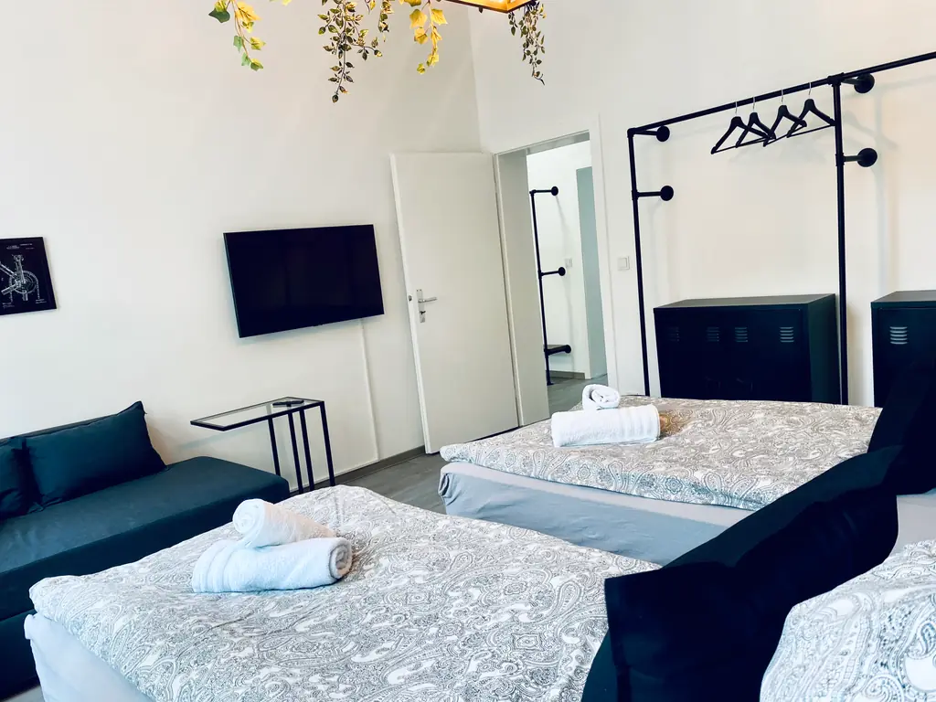 SH Team 1.0: Schlafzimmer mit Einzelbetten, Sofa und Fernseher