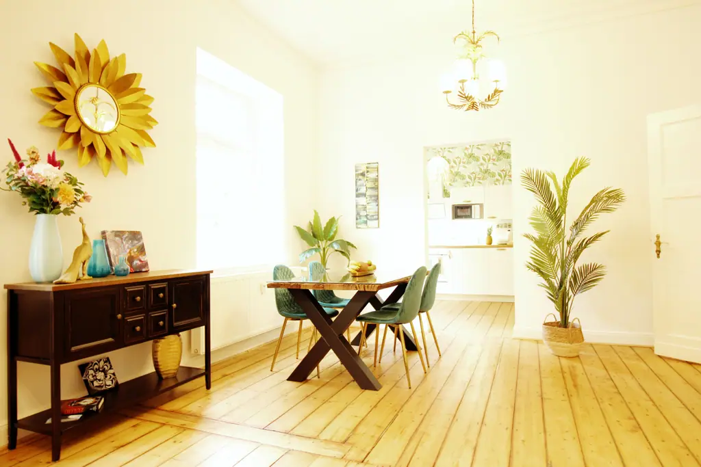 Essbereich mit Holztisch, Sideboard und goldenem Sonnenspiegel