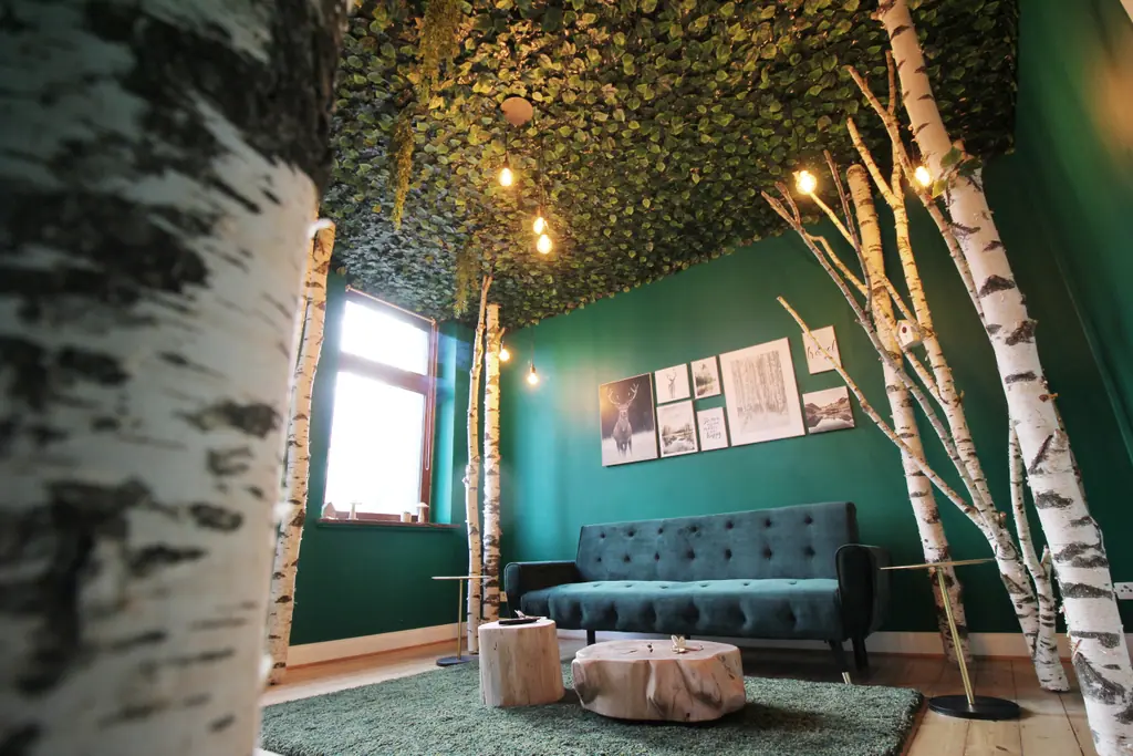 Wood Lodge: Wohnzimmer mit Birkenstämmen, grünen Wänden und Sofa